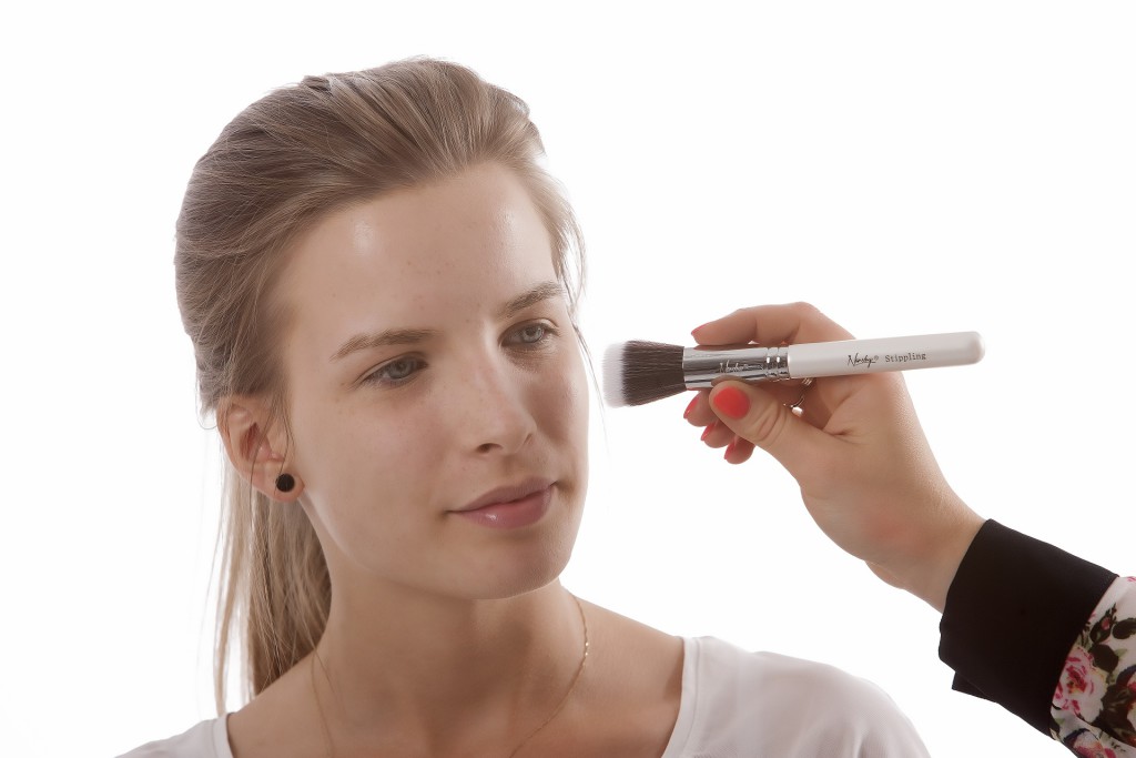 Femme se faisant maquiller avec un pinceau.