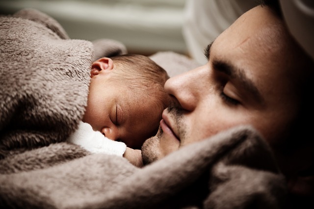 Un homme fait la sieste avec son nouveau-né.