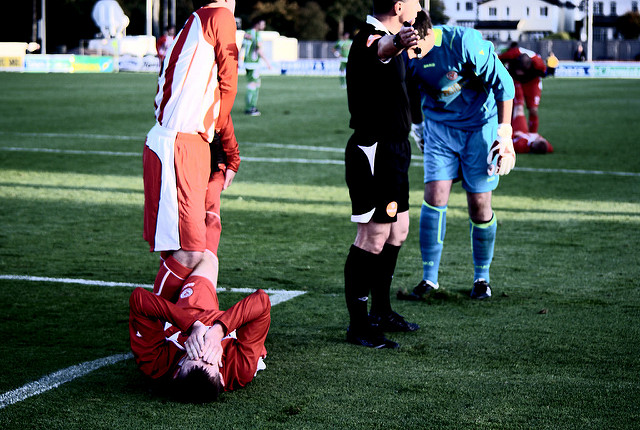 Un footballeur au sol souffrant d'une crampe à la jambe.