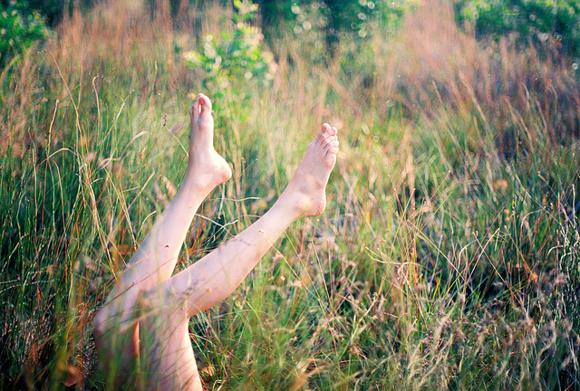 Jeune femme allongée dans l'herbe, les pieds en l'air.