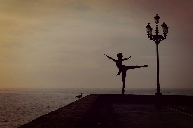 Danseuse classique près de la mer avec coucher de soleil.