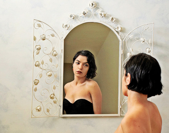 Une jeune femme se regarde dans un miroir.