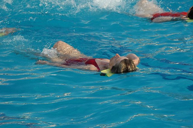 Femme en train de nager dans une piscine.
