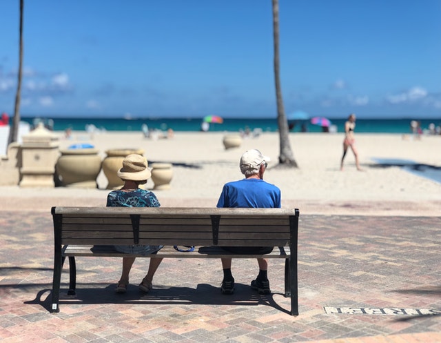 Personnes âgées face à la mer assis sur un banc.
