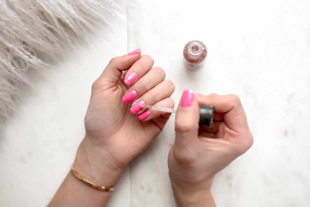 Femme en train de mettre du vernis sur ses ongles.