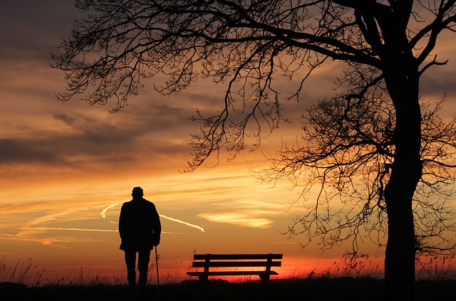 Personne âgée devant un coucher de soleil.